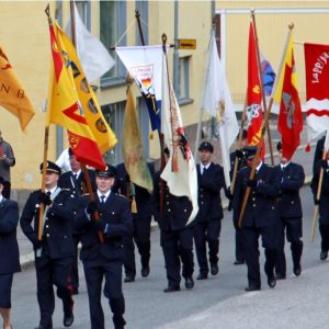 Avtalsbrandkårister marscherar med flaggor på gatan