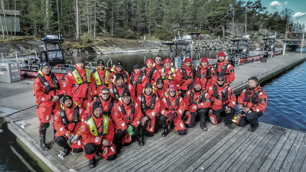 16 pelastajaa laiturilla veneasut ja pelastusliivit päällään.