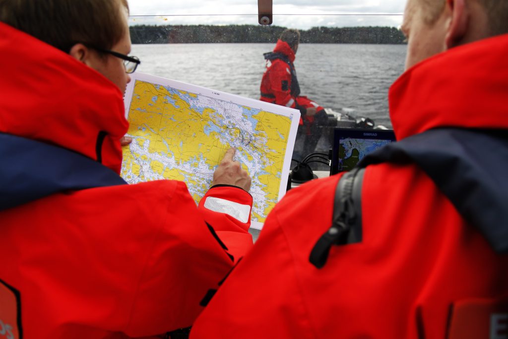 Pelastajia veneessä katsomassa merikarttaa.