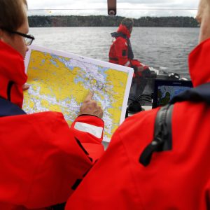 Pelastajia veneessä katsomassa merikarttaa.