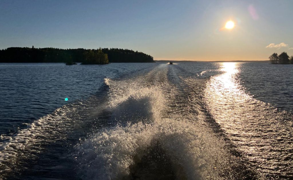 Järvimaisema ja veneen perässä syntyvä aallokko.