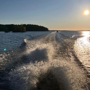 Järvimaisema ja veneen perässä syntyvä aallokko.