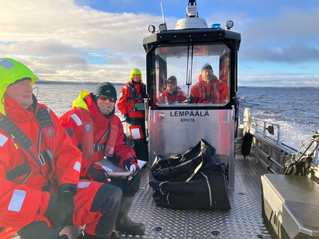 Pelastushenkilöstöä istumassa veneen kyydissä.