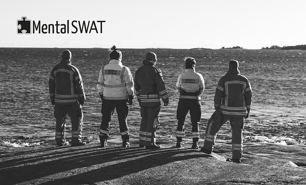 Mental SWAT -logo. Viisi pelastajaa ja ensihoitajaa seisovat kalliolla katsellen merelle.