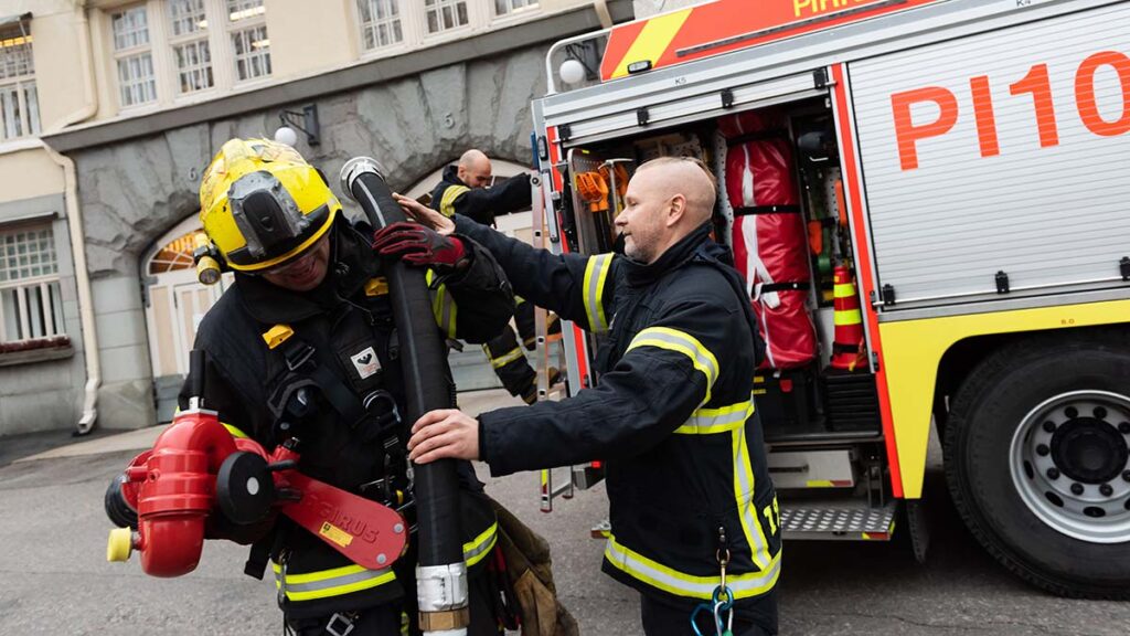 Pelastajia paloauton luona pukemassa päälleen sammutusasuja.